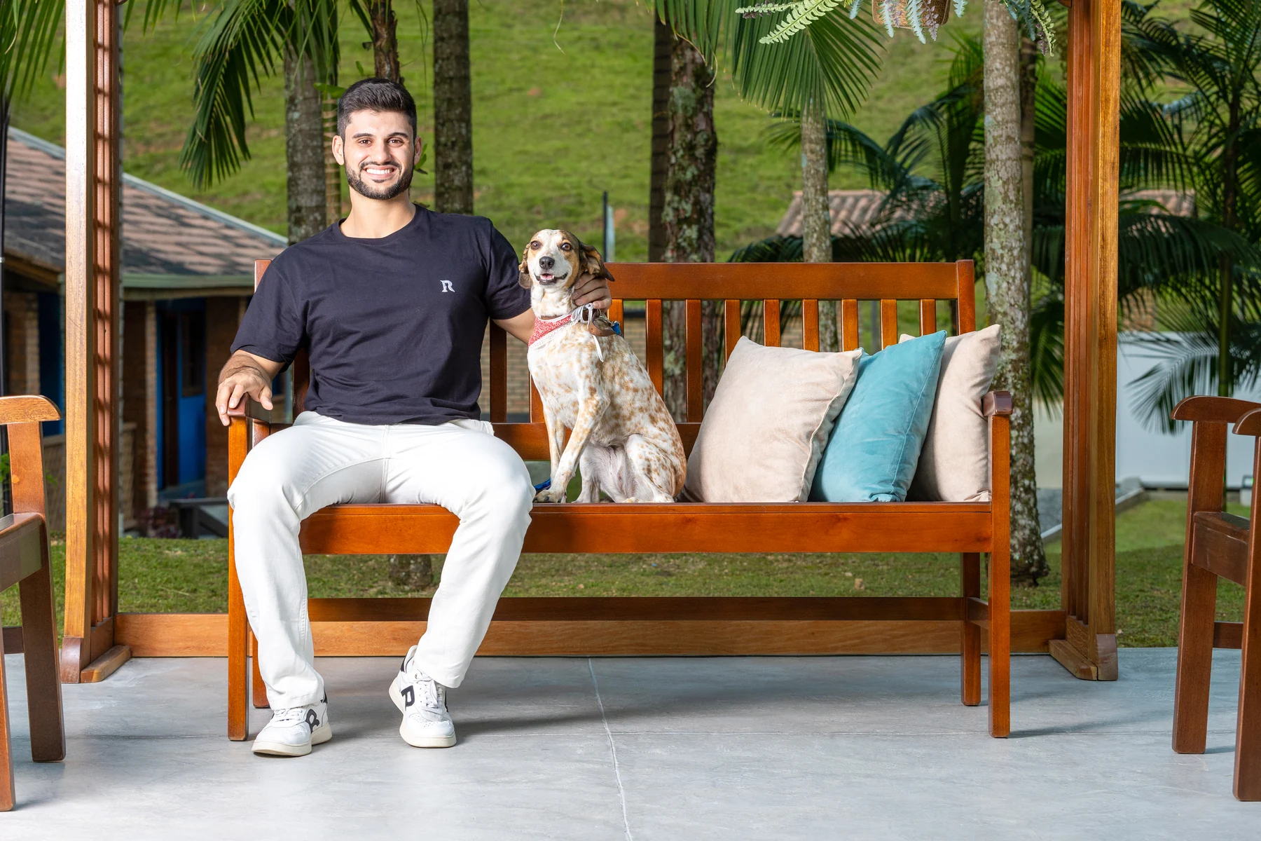 Pessoa e cachorro sentados em um banco de madeira da Móveis Daniella no jardim