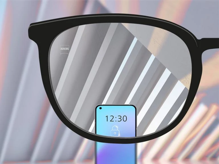Lente de visão simples ZEISS representada diante de um celular e do ambiente