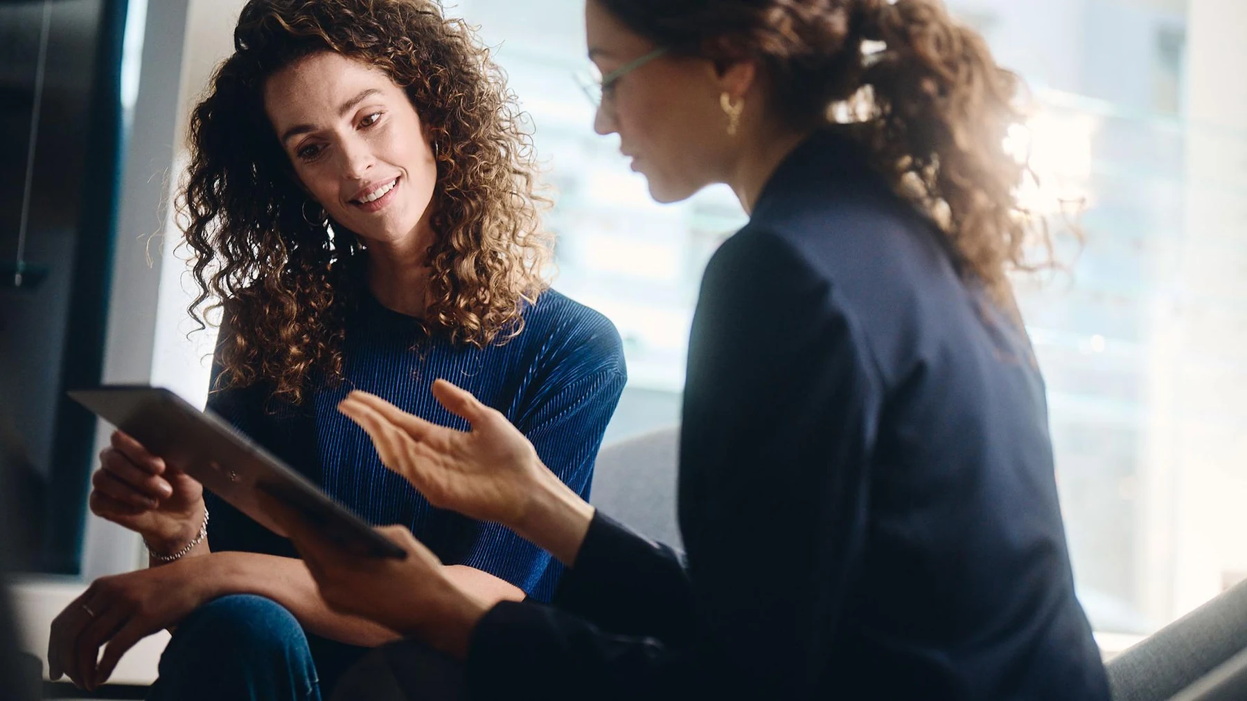 Duas mulheres conversam com o apoio de um tablet em uma cena de atendimento ZEISS.